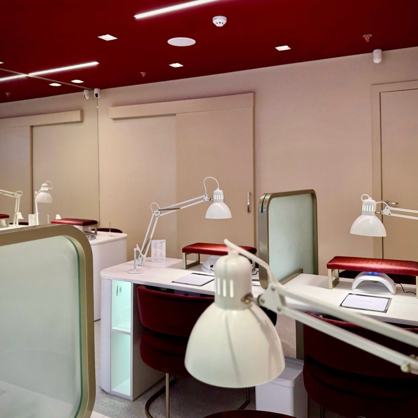 Interior do estúdio, com bancadas brancas, poltronas em veludo vinho e teto vermelho